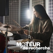 Une jeune femme joue de la batterie.