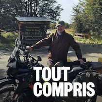 Un homme se tient debout à côté de sa moto.