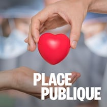 Deux mains se donnent un cœur devant des chirurgiens qui font une transplantation.