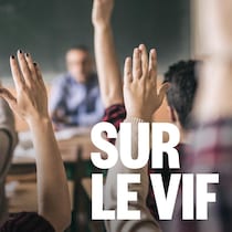 Des mains levées dans une classe.