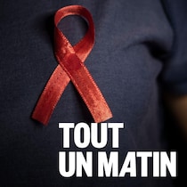 Une peronne porte le ruban rouge du VIH.