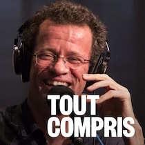 Un homme assis en studio derrière un micro le sourire au visage.