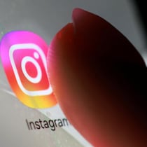 Un doigt appuie sur l'icône de l'application Instagram.
