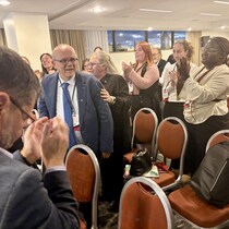 Émile Gallant est applaudit par une foule dans une salle de conférence.