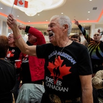 Un homme brandit un drapeau canadien et porte un t-shirt du mouvement « Canadiens pour toujours ».