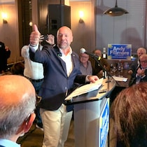 Dans un bar, entouré de partisans, Andy Fillmore se tourne vers sa droite et lève le pouce.