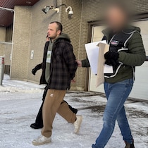 Une personne est escortée par des policiers.