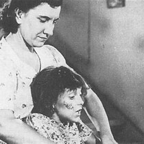 Une femme tient une petite fille par-derrière. 