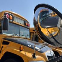 Le reflet d'un autobus scolaire dans un rétroviseur.