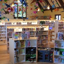 L'intérieur d'une bibliothèque; des oiseaux en origami sont accrochés au plafond.