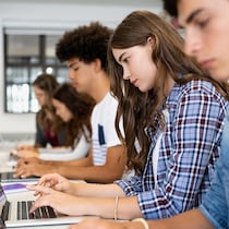 Des jeunes hommes et femmes sont assis dans une pièce devant leur ordinateur.