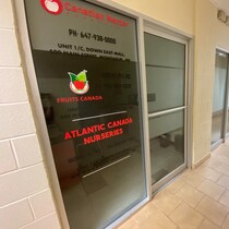 Une porte vitrée le long d'un couloir. Les noms des entreprises sont écrits sur la porte.