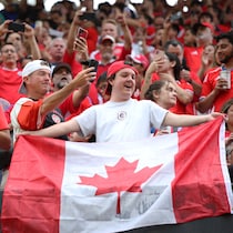 Des supporteurs dans des tribunes avec un drapeau du Canada.