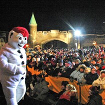 Sur scène, Bonhomme prend le temps de saluer la foule qui déborde de la place d'Youville sous le feu des projecteurs avant le début du spectacle.
