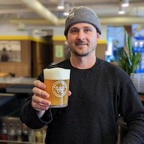 Le copropriétaire de la brasserie Whistle Buoy de Victoria, Isaiah Archer, présente un verre de la bière Robo Beer, dont la recette a été élaborée par intelligence artificielle, à Victoria, en février 2023.
