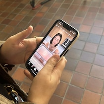 Une femme tient un cellulaire.