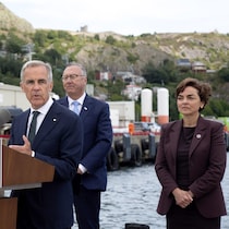 Mark Carney s'exprime à un pupitre, entouré de Tony Wakeham et de Christine Fréchette, sur un quai.