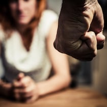 Le poing menaçant d'un homme devant la silhouette d'une femme.