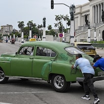 Trois hommes poussent une voiture.