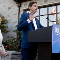 David Eby est devant un pupitre aux côtés de sa femme Cailey Lynch lors de l'annonce du déclenchement des élections provinciales.