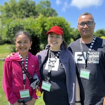 Une photo de famille avec une adolescente et ses parents, en plein air sur la pelouse.