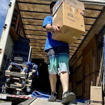 Un homme sort des boîtes d'un camion de déménagement.