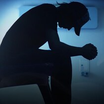 Un homme assis la tête baissée.
