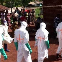 Des personnes portent des blouses et équipements de protection.