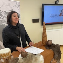 Édith Cloutier debout dans une salle devant des artéfacts autochtones.