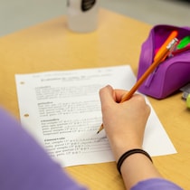 Une élève écrit des verbes sur une feuille.