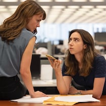 Deux femmes participent à un appel téléphonique et se regardent d'un air grave.