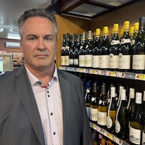 Un homme devant des bouteilles de vin.