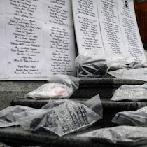 Des souliers sur des marches, devant une liste de noms de victimes de féminicide. 