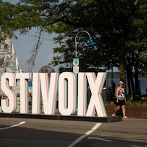 Une femme marche près d'une enseigne du FestiVoix.