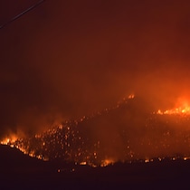 Des flammes s’attaquant à une montagne pendant la nuit.