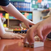 Des enfants jouent avec un train miniature au sol.