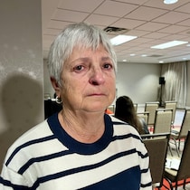 Gisèle Caissie, les yeux rougis, dans une salle de réunion.