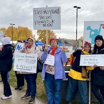 Des manifestants tiennent des pancartes mentionnant « le communautaire à boutte ».