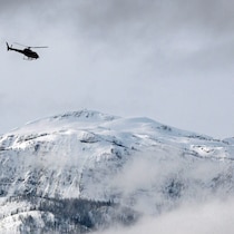 Un hélicoptère survole une montagne.