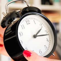 Une femme recule l'heure d'une horloge.