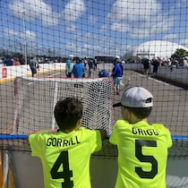 Deux jeunes regarde une partie de hockey-balle.
