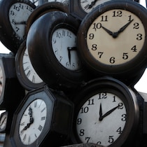 Une sculpture composée de plusieurs horloges indiquant des heures différentes.