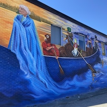 Une peinture d'une grand-mère sur un canot avec des rameurs à tête d'oiseau sur un bâtiment.