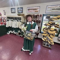 Un jeune homme déguisé en Anne Shirley dans un magasin tient un sac et un bouquet de fleurs.