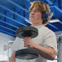 Un jeune homme fait des haltères dans un gym.