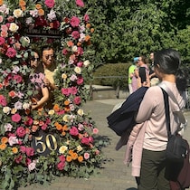 Une jeune fille prend en photo un couple dans un cadre fleuri.