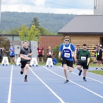 Quatre para-athlètes, dont Olivier Thériault, courent sur la piste d'athlétisme.