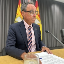 Un homme assis devant des drapeaux du Nouveau-Brunswick.