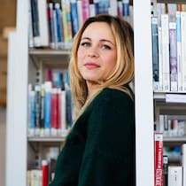 Julie Gillet dans les rangées de livres d'une bibliothèque.