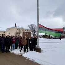 Une quarantaine de personnes sont rassemblées autour du drapeau panafricain.